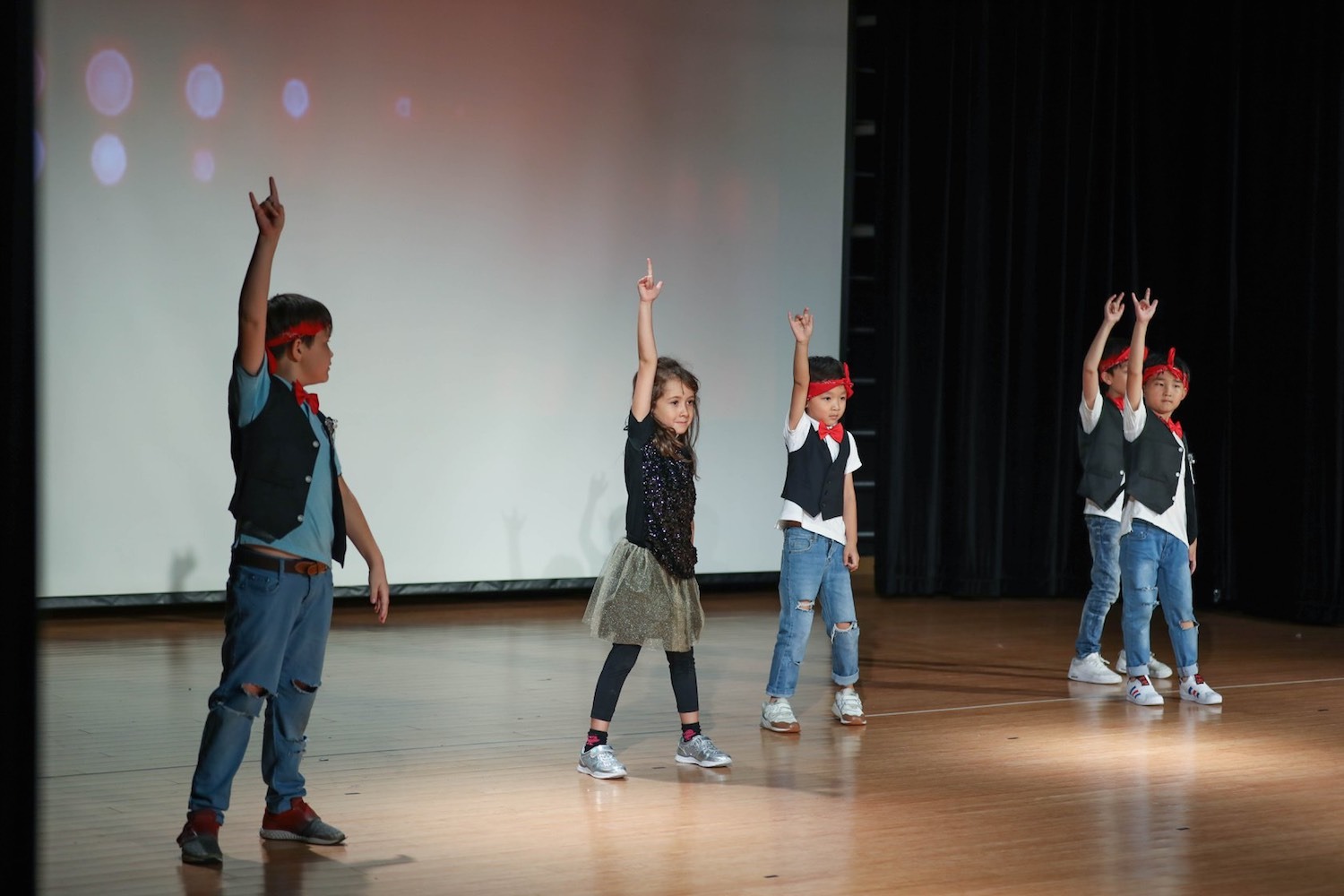 four dancers performing with hands in the air